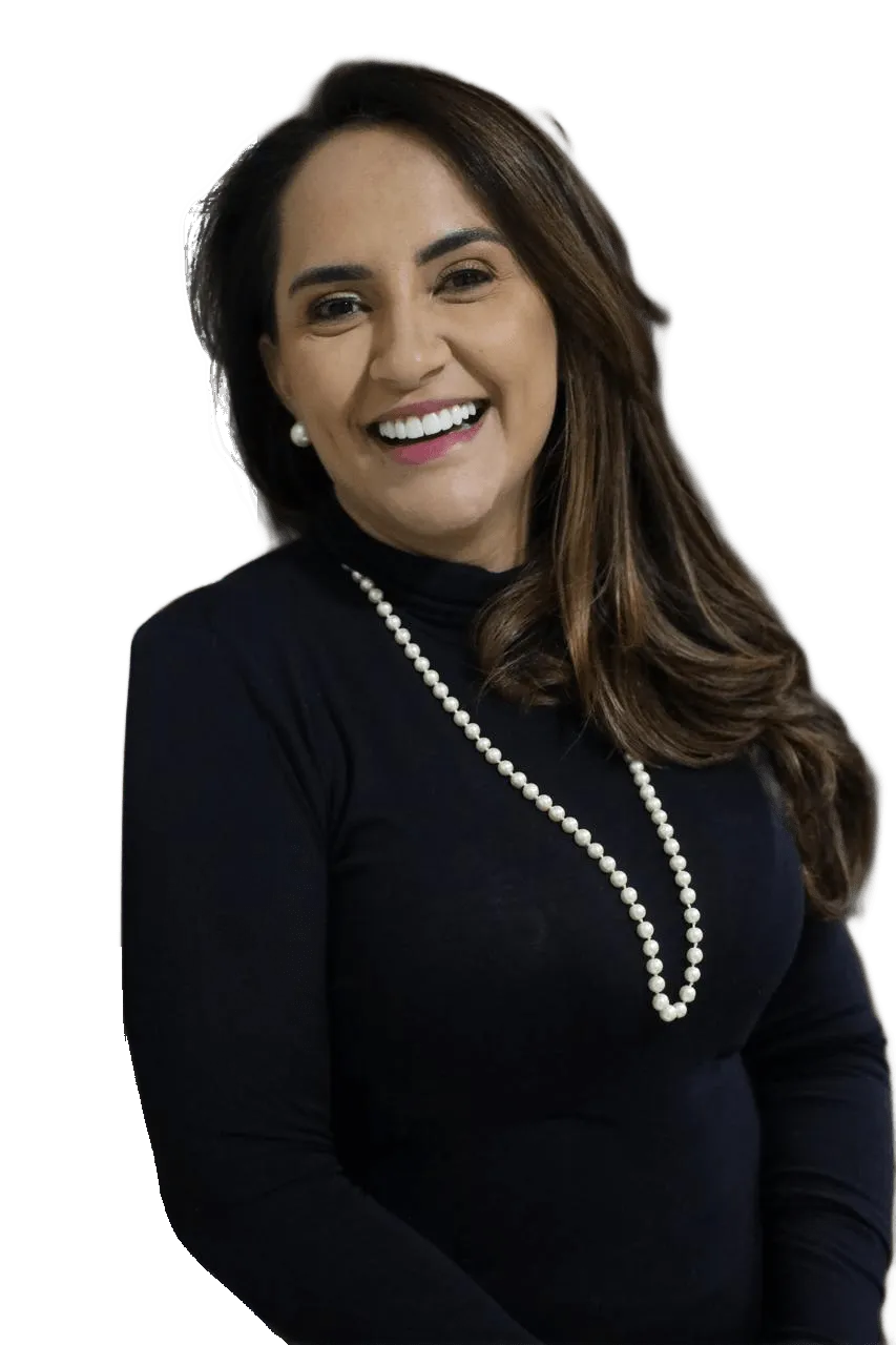 Retrato da Dra. Paula Trindade, advogada previdenciária, sorrindo, de blusa preta de gola alta e colar de pérolas.